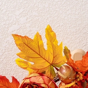Detailed view of autumn wreath with maple leaves berries and a white pumpkin decor