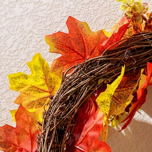 Detail of autumn wreath featuring realistic maple leaves on a natural vine base