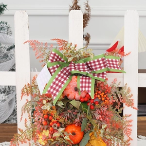 Autumn harvest door wreath with plaid bow, orange pumpkins and fall leaves on white fence