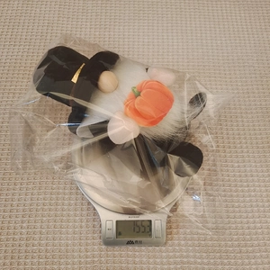 Detailed view of Harvest Festival gnome plush with orange pumpkin on a digital scale