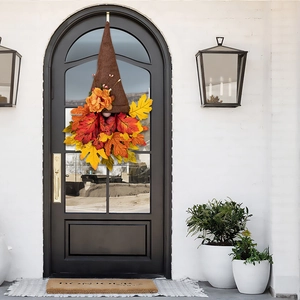 Detail of autumn gnome wreath with orange maple leaves and fabric hat on front door