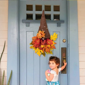Detail of harvest gnome door wreath with faux maple leaves on a blue wooden door