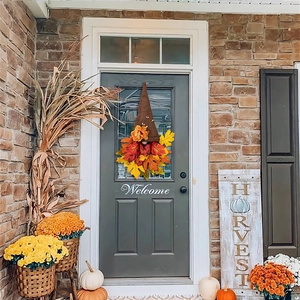 Close-up of autumn harvest gnome wreath with colorful maple leaves on dark front door