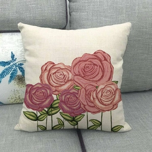Dettaglio della federa in lino con motivo a rose su un divano in tessuto grigio