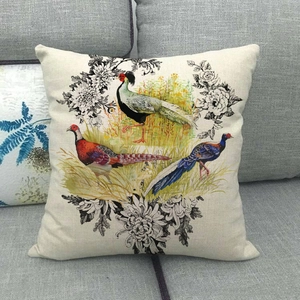 Detail of linen cushion cover featuring birds and flowers on a gray fabric sofa