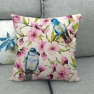 Detail of linen cushion cover featuring blue birds and pink cherry blossoms on a sofa