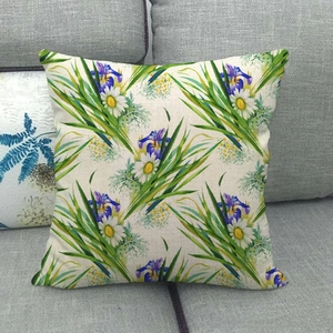 Funda de cojín de lino con estampados de hojas y flores sobre un sofá gris