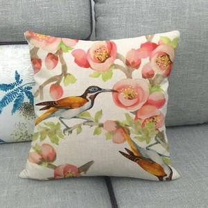 Linen blend throw pillow case with floral and bird prints on a gray living room sofa
