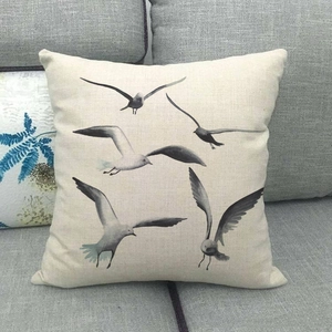 Detail of linen pillowcase with grey seagulls pattern on a grey fabric sofa