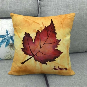Close-up of a linen autumn pillowcase with a red leaf and Autumn text on a grey sofa
