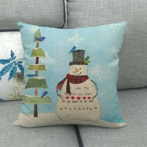 Close-up of rustic snowman Christmas cushion cover on a grey sofa with holiday greetings
