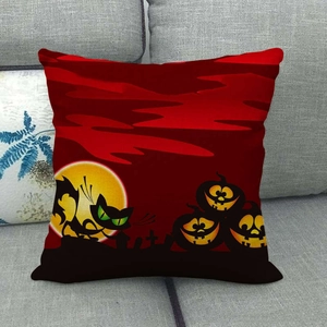 Detalle de funda de cojín roja de Halloween con gato negro y calabazas en sofá gris