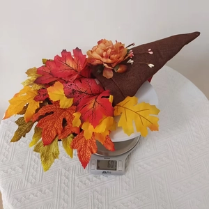 Detailed view of autumn harvest wreath showing lifelike maple leaves and flower weight