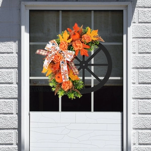 Fall wreath with orange pumpkins, roses and maple leaves on a black wheel frame