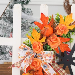 Autumn wreath with pumpkins and orange maple leaves on a white wooden fence