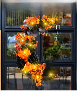 Detail of moon-shaped Halloween wreath with orange flowers, black cat, and LED lights