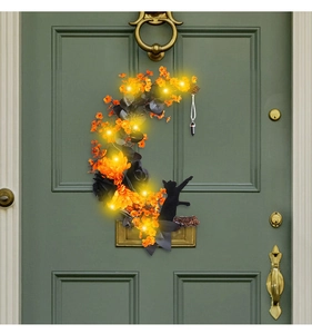 Detail of Halloween moon wreath with black cat silhouette and LED lights on a green door