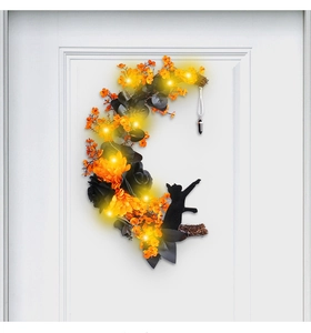 Detail of Halloween moon wreath with black cat, orange flowers and warm LED lights