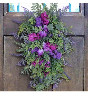 Detailed view of artificial purple tulip swag hanging on a vintage dark wooden door