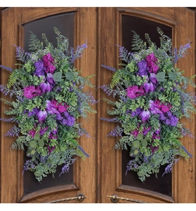 Detail of two purple tulip and lavender wreaths hanging on a dark wooden front door
