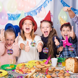 Close-up of birthday squad tin badges worn by children in a festive party celebration