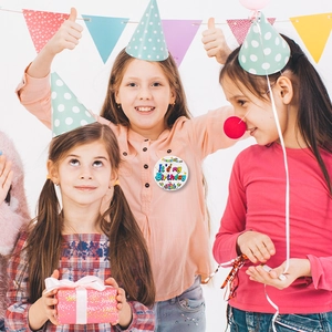 Child wearing It's My Birthday pin badge during a festive birthday party celebration