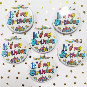 Close-up of 6-piece rainbow birthday button set with festive balloons and gift boxes
