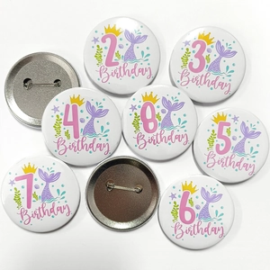 Detailed view showing front mermaid patterns and back metal pin of birthday badges