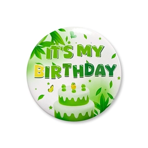 Macro view of a tinplate birthday badge with a green cake and It's My Birthday text