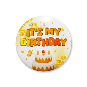 Close-up of birthday tinplate badge with It's My Birthday text and cake illustration