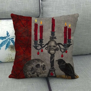 Detail of gothic linen pillowcase with skull, red candles, and crow on grey sofa