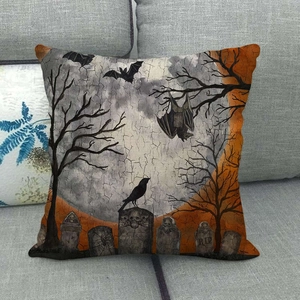 Detail of linen Halloween pillow cover with cemetery scene and bats on a grey sofa