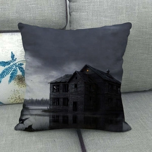 Detail of linen pillowcase featuring a gothic haunted house design on a gray sofa