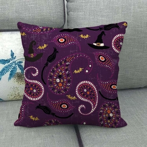 Close-up of a purple Halloween pillow cover featuring a witch hat and bat on a grey sofa