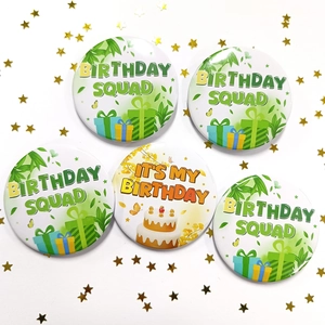 Close-up of birthday tinplate badges set with Birthday Squad and It's My Birthday text