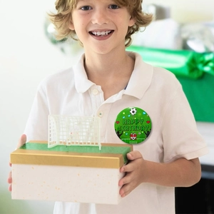 Detail shot of a football-themed happy birthday tin badge worn on a white polo shirt