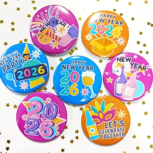 Detail showing various 2026 Happy New Year tinplate badges with party fireworks designs