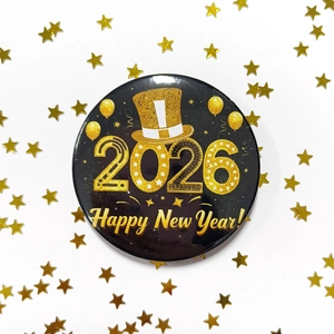 Macro shot of 2026 Happy New Year black and gold tinplate badge with festive sparkles