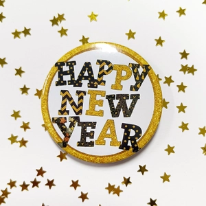 Detail of round Happy New Year badge with gold glitter border and star sequins