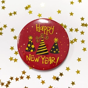 Macro shot of red Happy New Year badge with black party hats and gold star sequins