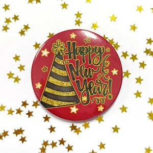 Macro shot of red Happy New Year tinplate badge with gold stars for party decoration