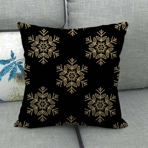 Detail of black linen pillowcase featuring a golden snowflake pattern on grey sofa
