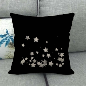 Detailed texture of black square linen pillowcase with silver star pattern on a sofa