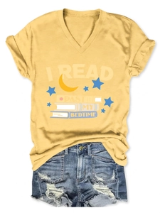 Flat lay of a yellow V-neck T-shirt with I Read Past My Bedtime slogan and denim shorts