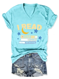 Flat lay of light blue V-neck tee with 'I READ PAST MY BEDTIME' and ripped denim shorts