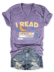 Flat lay of purple V-neck T-shirt with 'I READ PAST MY BEDTIME' print and denim shorts