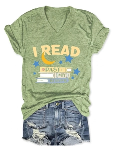 Flat lay of a green V-neck T-shirt with I Read Past My Bedtime print and denim shorts