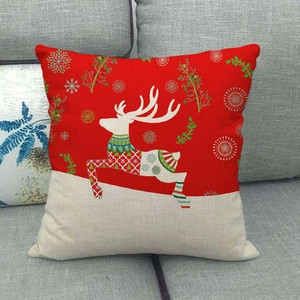 Detail of linen Christmas pillowcase with red and white reindeer print on a sofa
