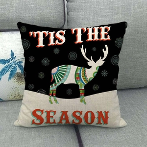 Detail of Christmas reindeer pillow case with geometric patterns on a grey fabric sofa