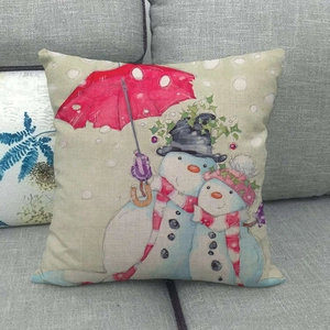 Close-up of a festive linen pillowcase featuring a snowman with a red umbrella on a sofa